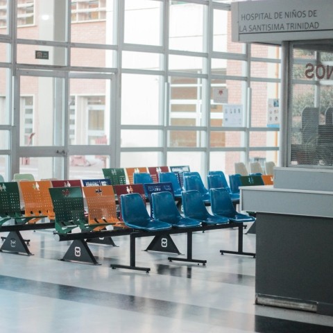 A waiting room with multi-colored chairs and a wall of windows.